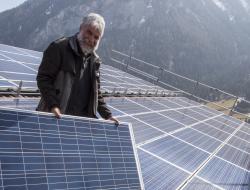 Christian Hassler bei der Montage von Photovoltaikmodulen auf einem Welleternitdach in der Alpenregion Graubündens.